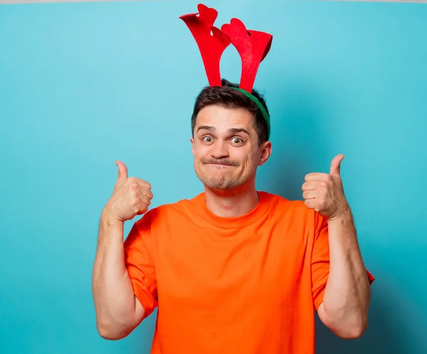 Ο άνθρωπος σε πορτοκαλί μπλουζάκι με κέρατα ελαφιών Χριστούγεννα — Φωτογραφία Αρχείου