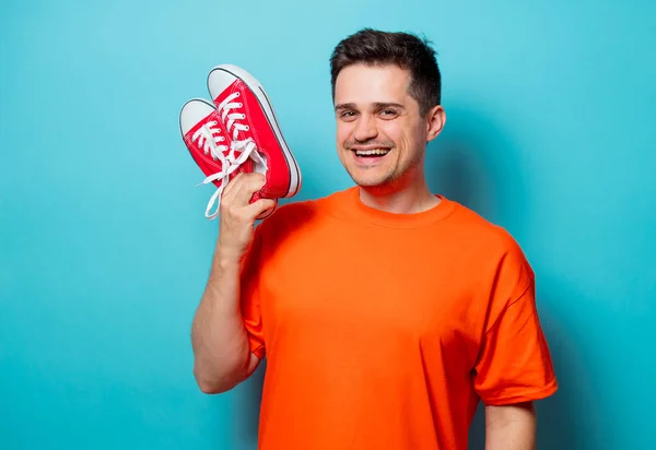 Knappe man in oranje t-shirt met rode gumshoes — Stockfoto