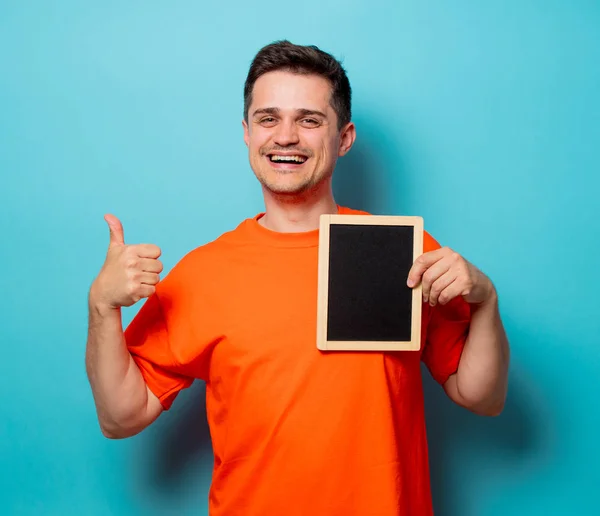 Mann in orangefarbenem T-Shirt mit kleiner Tafel — Stockfoto