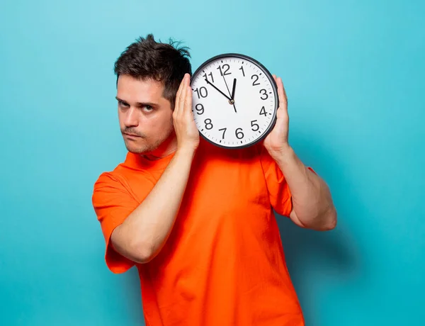 Man in orange t-shirt with big clock — Stock Photo, Image