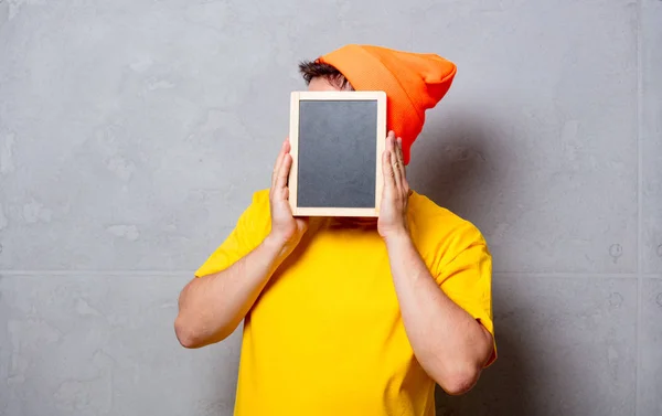 Homme en t-shirt jaune avec tableau noir — Photo