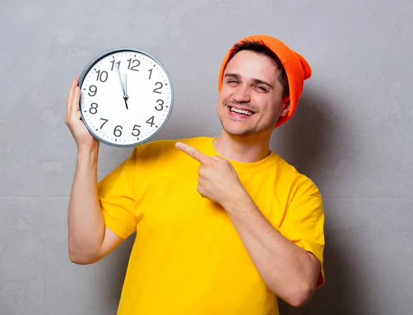 Man in geel t-shirt en muts met grote klok — Stockfoto