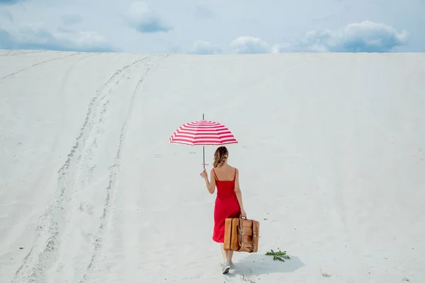 Röd klänning med paraply och resväska på stranden — Stockfoto