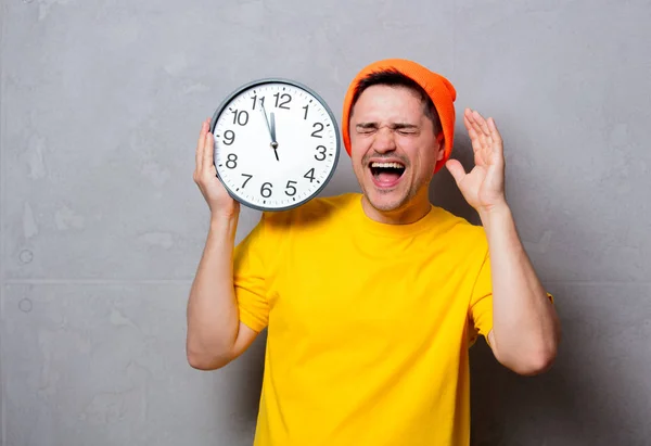 Homme en t-shirt jaune et chapeau avec grande horloge — Photo