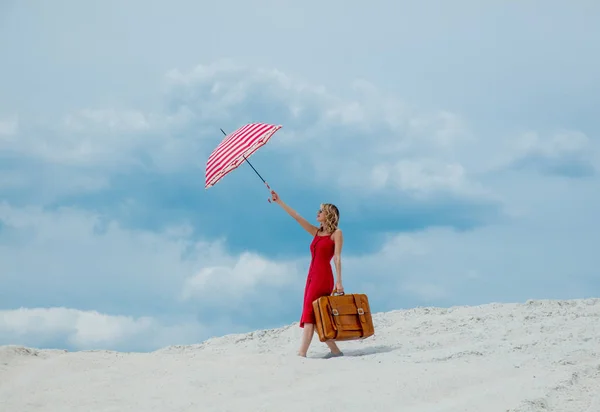 Piros ruha, napernyő és a bőröndöt, a strandon — Stock Fotó