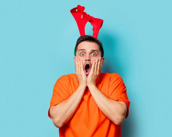 Homem em camiseta laranja com chifres de veado de Natal — Fotografia de Stock