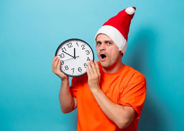 Homme avec chapeau de Noël et grande horloge — Photo