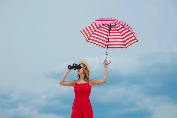 Woman in red dress with umbrella and binoculars — Stock Photo, Image