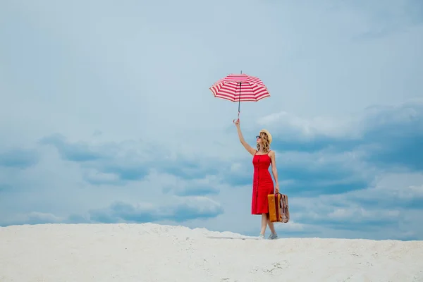 Vestido rojo con paraguas y maleta en la playa —  Fotos de Stock