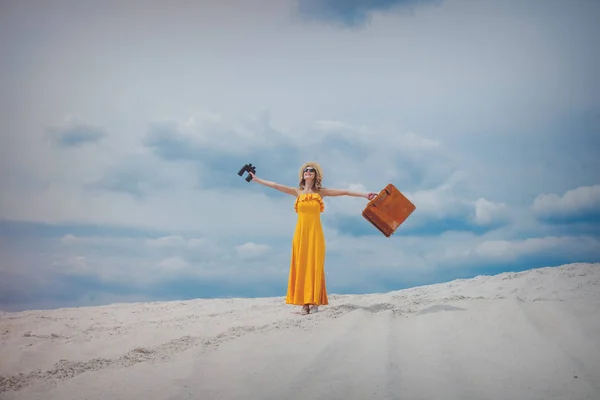 Žena ve žlutých šatech s kufrem a dalekohledy — Stock fotografie