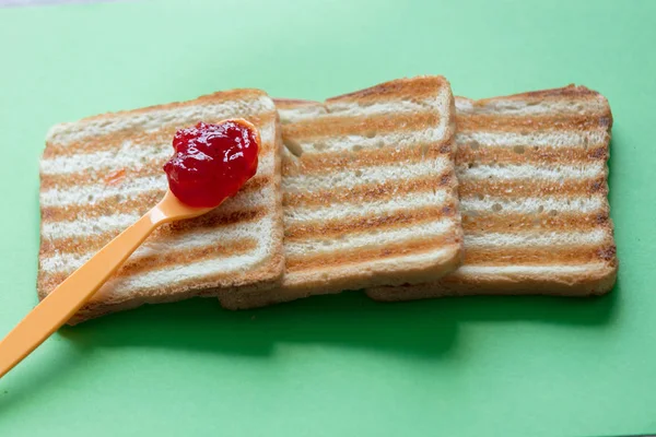 Fatias de pão torrado e colher de chá com geléia — Fotografia de Stock