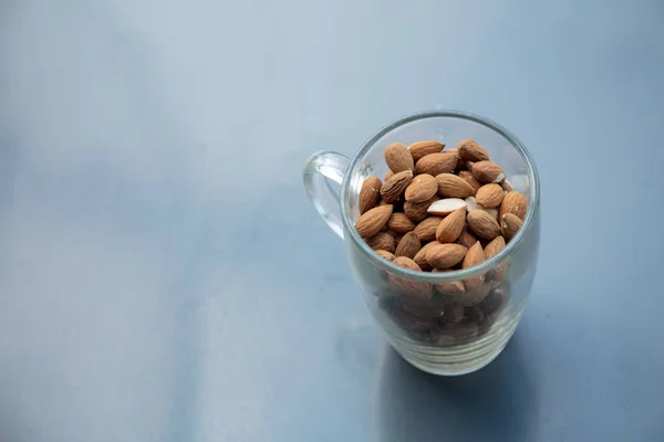 Glass cup and almonds on metal grey background — Stock Photo, Image