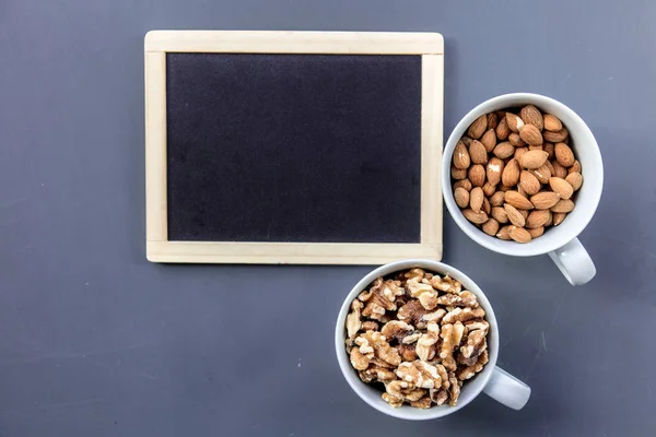 White cups full of almonds and walnuts — Stock Photo, Image