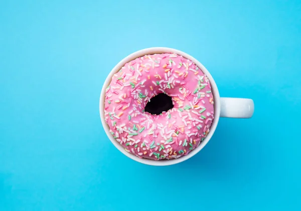 파란색 배경에 컵에 크림 도넛 — 스톡 사진