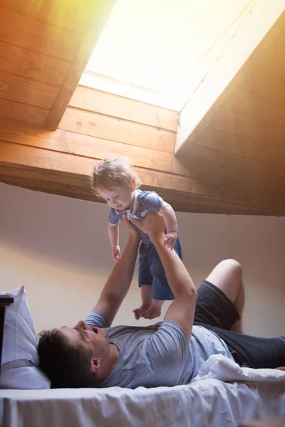 Jeune père heureux et enfant jouent dans un lit — Photo