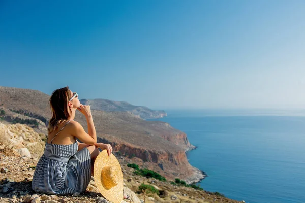 Girl in hat and dress with sea coastline — Stock Photo, Image