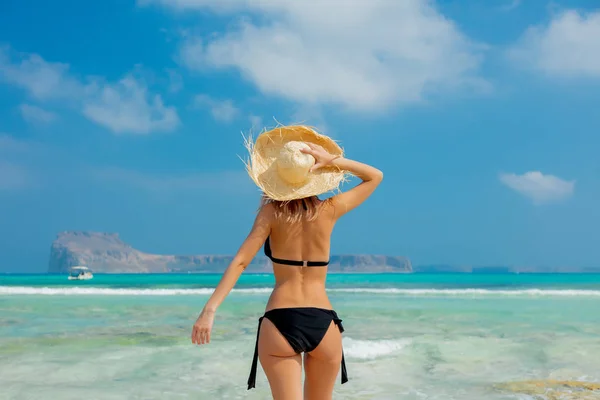 Девушка в черном бикини и в шляпе на пляже Балос — стоковое фото