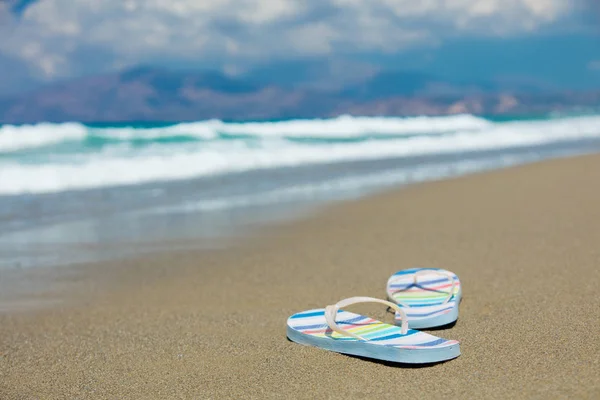 Färgade sandaler på sanden på stranden — Stockfoto