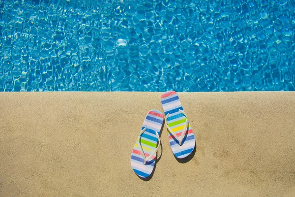 Sandálias de verão coloridas perto da piscina azul — Fotografia de Stock