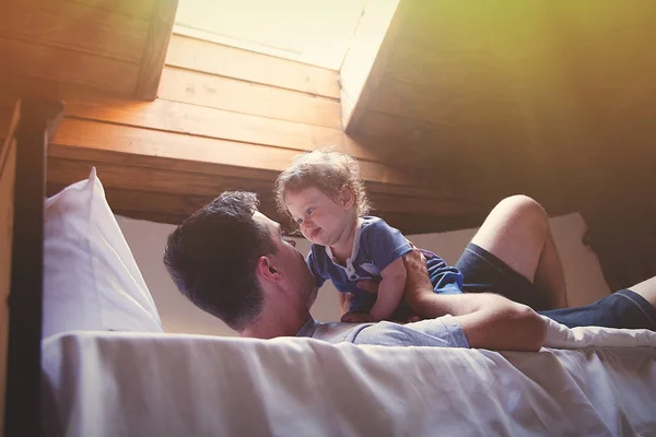 若い幸せな父と子がライトが付いているベッドで再生ウィンドウを形成します — ストック写真
