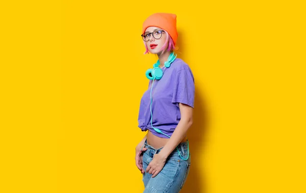 年轻时尚的女人穿着紫色的衣服与耳机在黄色背景 二十世纪八十年代款式服装 — 图库照片