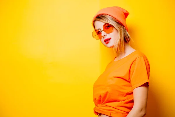 年轻的时尚女人 橙色眼镜黄色背景 二十世纪八十年代款式服装 — 图库照片