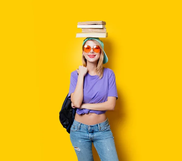 黄色の背景にオレンジ色のメガネと本を持つ若いスタイルの学生の女の子 1980年代の服装 — ストック写真