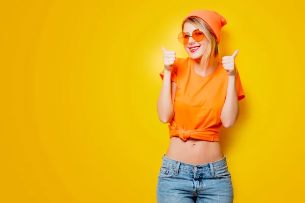 黄色の背景に親指で若い幸せな女 1980 年代スタイルの服 — ストック写真