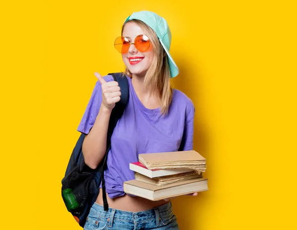 黄色の背景にオレンジ色のメガネと本を持つ若いスタイルの学生の女の子 1980年代の服装 — ストック写真