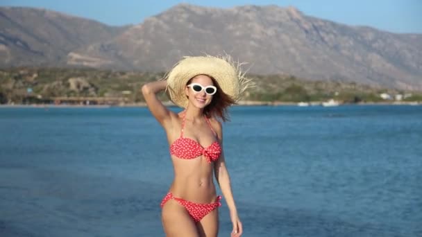 麦わら帽子と水着の砂浜のビーチでポーズ美しい若い女性 — ストック動画