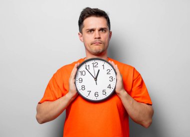 Büyük saat ile turuncu tişört genç yakışıklı adam. Beyaz arka plan resmine stüdyo