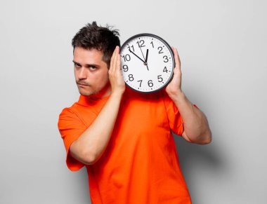 Büyük saat ile turuncu tişört genç yakışıklı adam. Beyaz arka plan resmine stüdyo