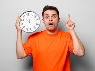 Büyük saat ile turuncu tişört genç yakışıklı adam. Beyaz arka plan resmine stüdyo