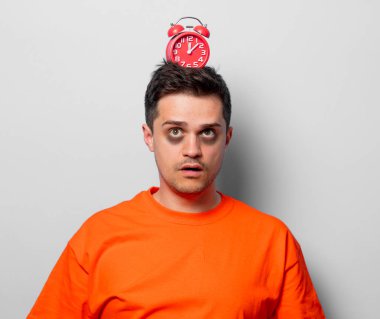 Kırmızı alarm saati ile turuncu tişört genç yakışıklı adam. Beyaz arka plan resmine stüdyo