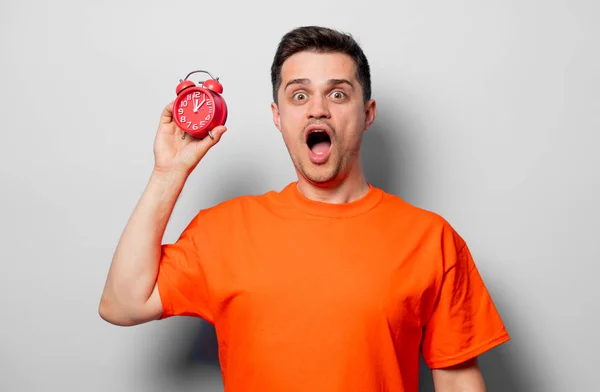 Jovem Bonitão Shirt Laranja Com Despertador Vermelho Imagem Estúdio Sobre — Fotografia de Stock