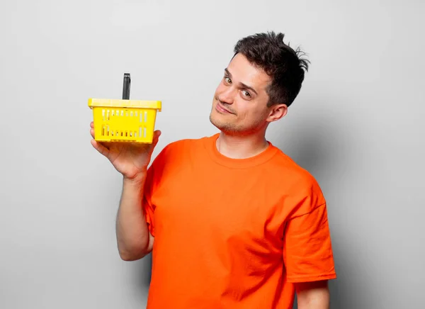 年轻英俊的男子在橙色 T恤与黄色 Sumermarket 白色背景上的工作室图像 — 图库照片