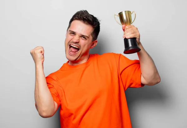 Junger Gutaussehender Mann Orangefarbenem Shirt Mit Goldener Tasse Studiobild Auf — Stockfoto