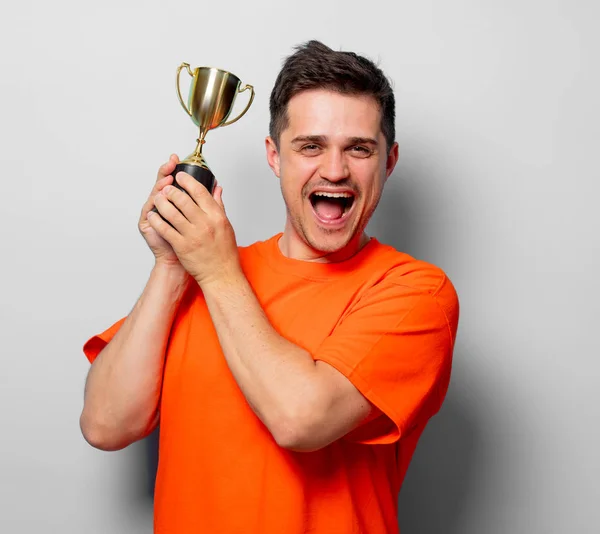 Junger Gutaussehender Mann Orangefarbenem Shirt Mit Goldener Tasse Studiobild Auf — Stockfoto