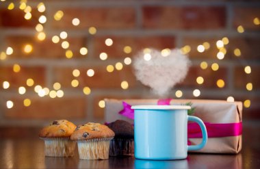 Ev yapımı klasik ve çikolatalı kek ve çay kalp ile buhar şekil. Peri ışıkları ve bokeh arka planda hediye kutusu