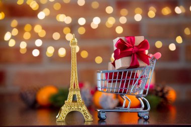 Altın Eyfel Kulesi Hatıra ve süpermarket tam bokeh peri ışıkları ile arka plan üzerinde mevcut hediye sepeti. Noel tatil sezonu