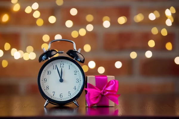 紫弓と背景のボケ味の妖精ライト木製テーブルの上の目覚まし時計と手作りギフト ボックス — ストック写真