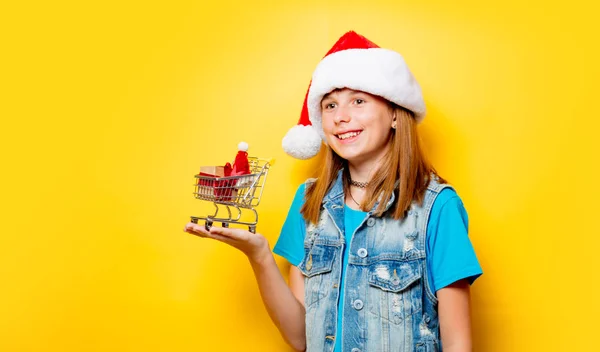 Menina em chapéu de Natal com carrinho de supermercado — Fotografia de Stock