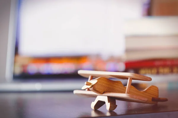 木制飞机玩具桌上有书本和笔记本电脑的砖墙背景 — 图库照片