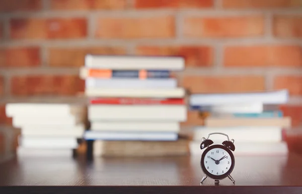 Kleiner Wecker auf einem Tisch mit Büchern — Stockfoto