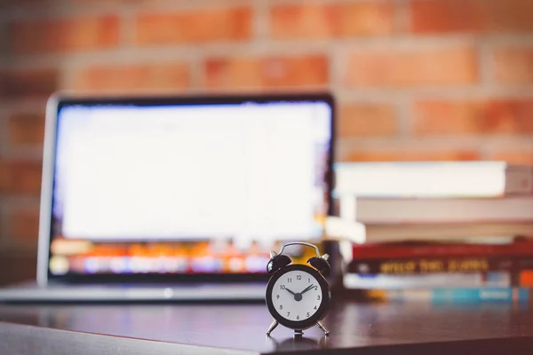 Alarm clock on a table with laptop computer and books — Stock Photo, Image