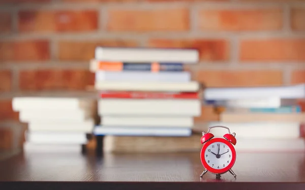 Kleiner Wecker auf einem Tisch mit Büchern — Stockfoto