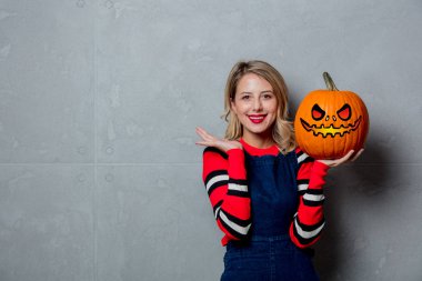 Cadılar Bayramı Balkabağı gri arka plan üzerinde ile kırmızı Çizgili kazaklı genç tarzı sarışın kız portresi.