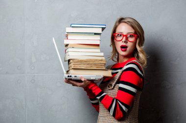 Dizüstü bilgisayar ve gri arka plan üzerine kitaplar ile genç kız. Kitaplar satın alınabilir Internet store üzerinden