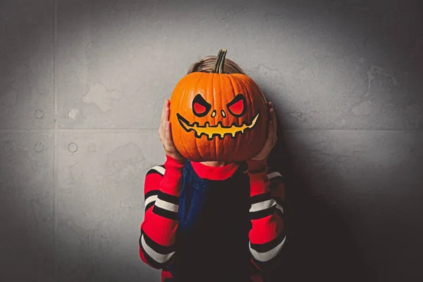 ハロウィンかぼちゃの灰色の背景に赤いストライプ セーターで若いスタイルのブロンドの女の子の肖像画 — ストック写真
