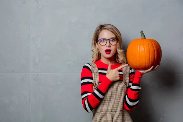 ハロウィンかぼちゃの灰色の背景に赤いストライプ セーターでスタイリッシュな金髪少女の肖像画 — ストック写真